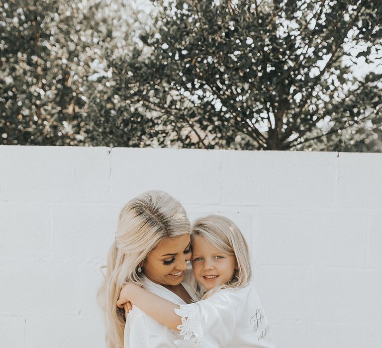 A bride cuddles her daughter as they get ready for her wedding. 