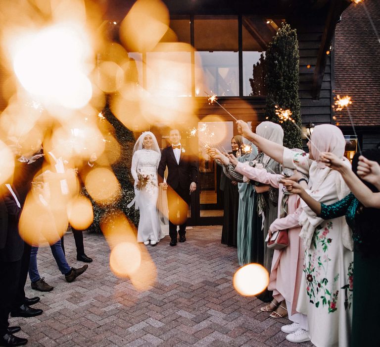 Bride and groom walk through sparkler send off from wedding guests