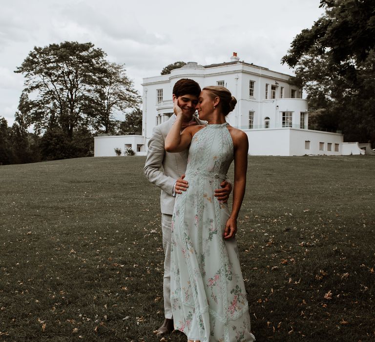 Bride leans back to hold groom as they both smile lovingly outside the Belair House