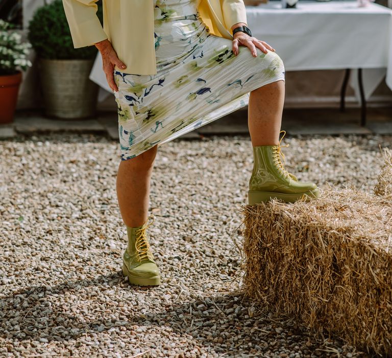 Wedding guest puts her leg up on hay bale for Park Farm wedding as the sun shines