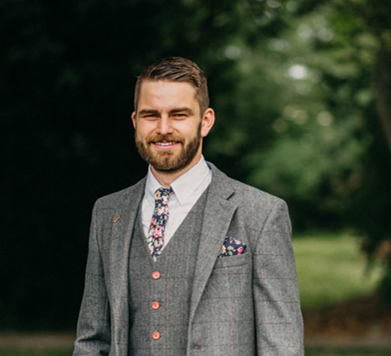 Groom in a mid grey wool blend check suit with pink pin stripe design 