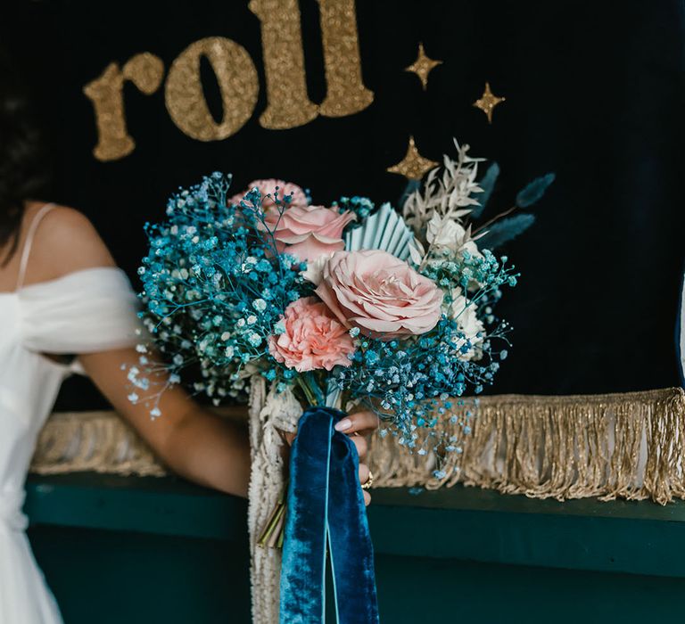 Pink roses and carnations and teal gypsophila wedding bouquet tied with ribbon 