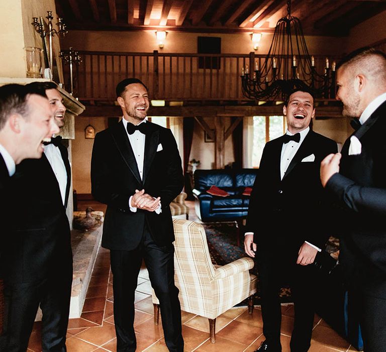 Groom laughs with his groomsmen as they wear black tie on the morning of wedding day