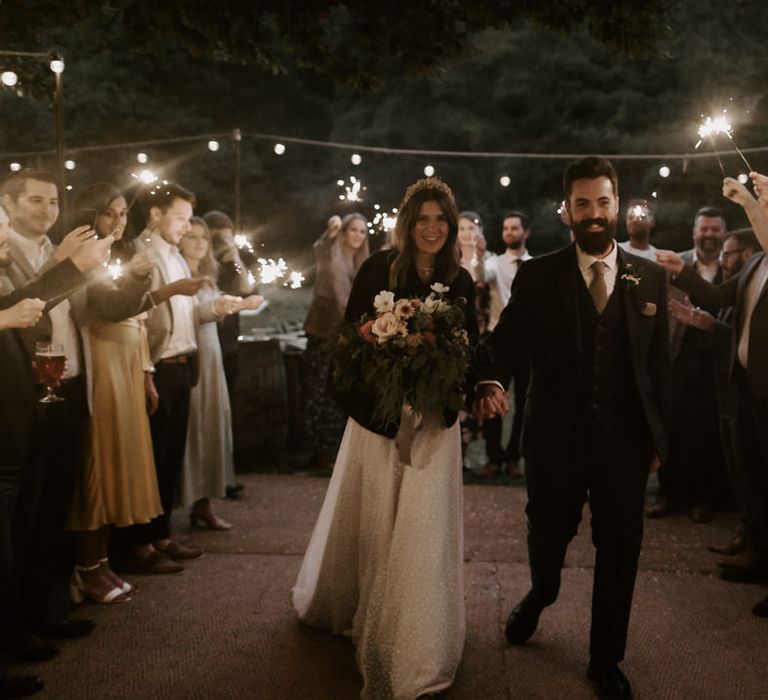 Bride & groom stand with their wedding party who hold sparklers