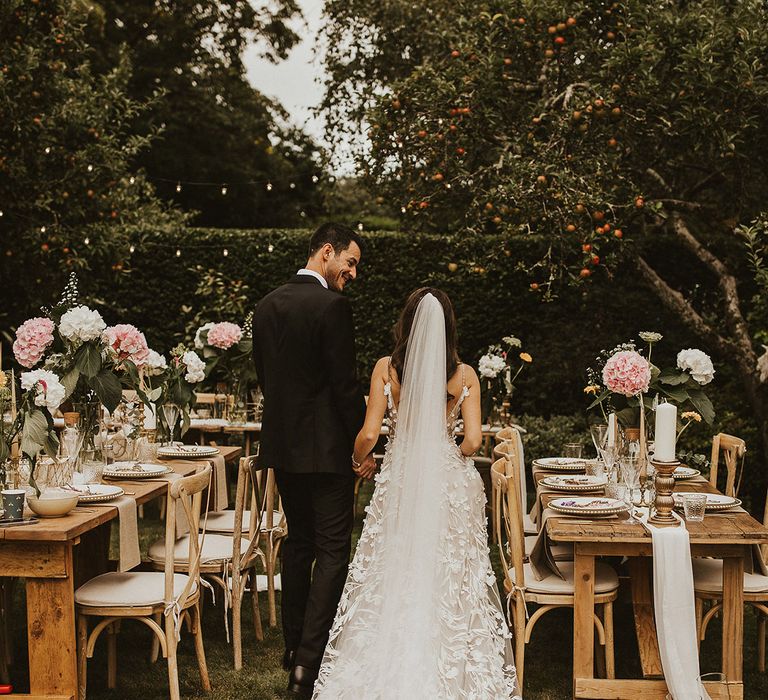 Bride & groom walk through reception garden with one another