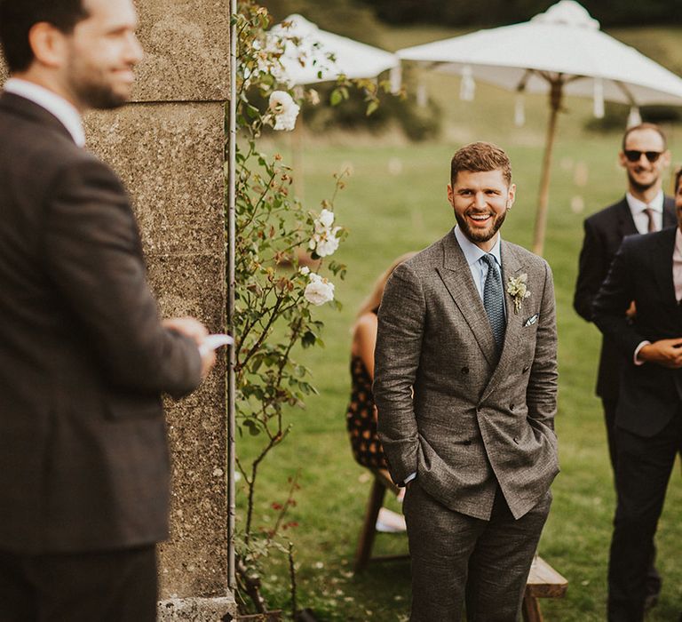 Groom smiles and laughs with friends on his wedding day