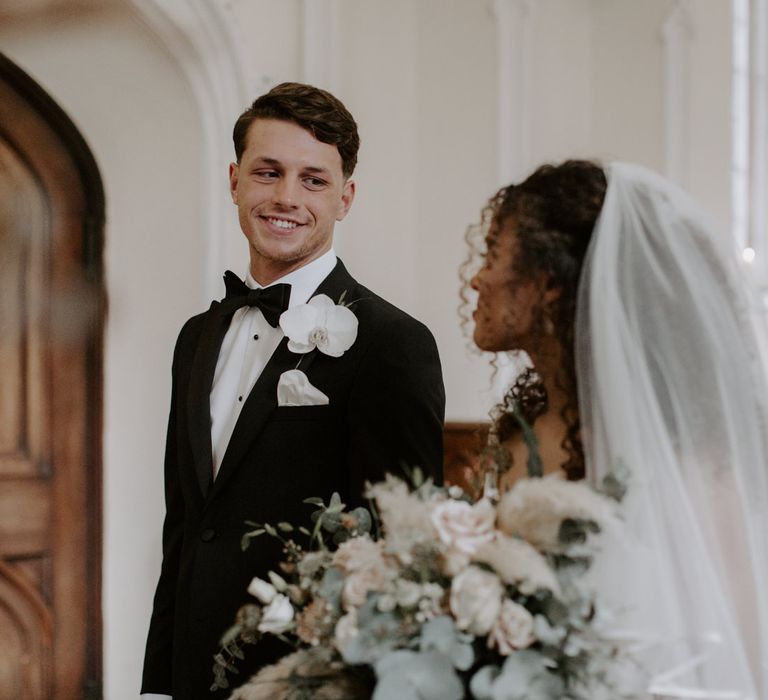 Bride looks lovingly at her groom as he looks down toward her whilst smiling