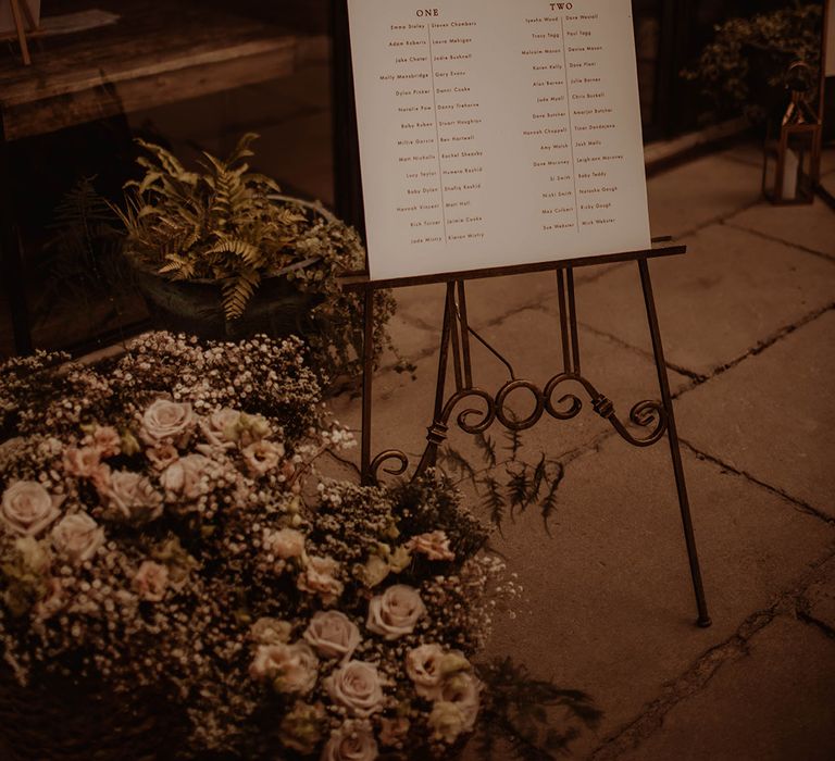 Wedding table plan on an easel surrounded by pink flowers and gypsophila 