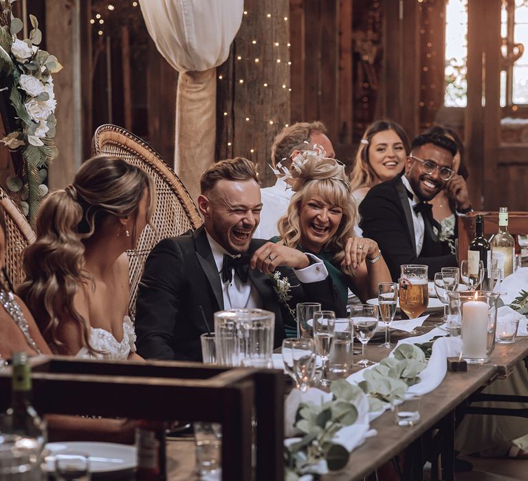 Groom laughs with family members on the day of his wedding during reception