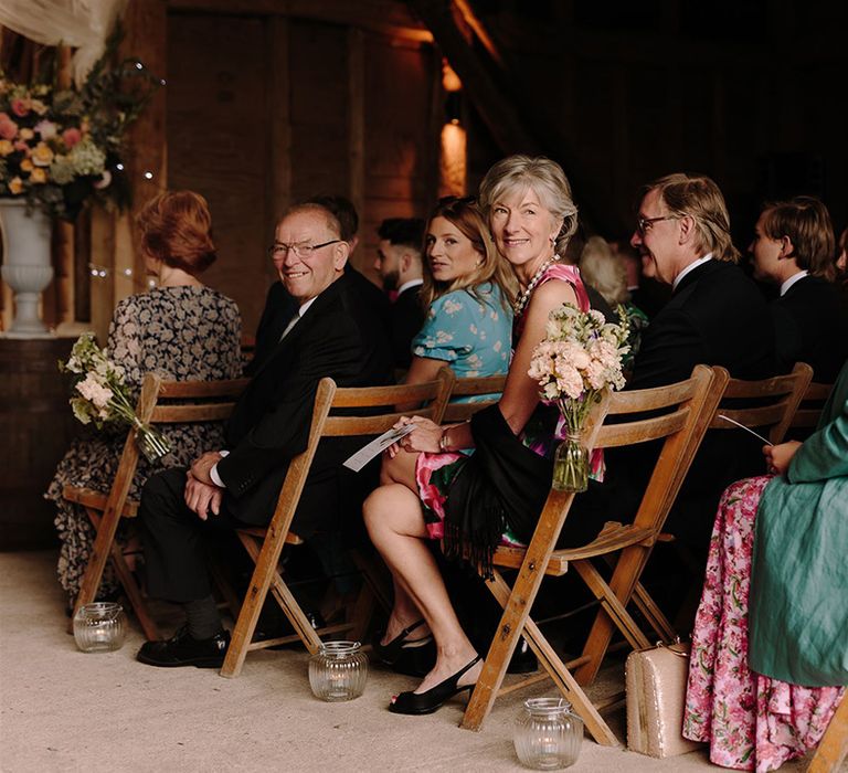 Wedding guests watch bride walk down the aisle at barn ceremony