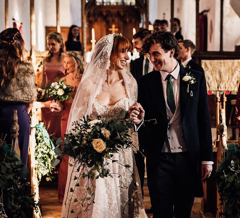 Bride carries large bouquet at church wedding ceremony