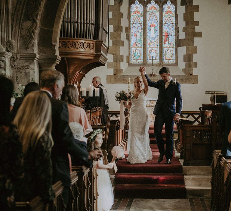 Bride and groom turn to face their wedding guests as a married couple in church venue with stained glass windows