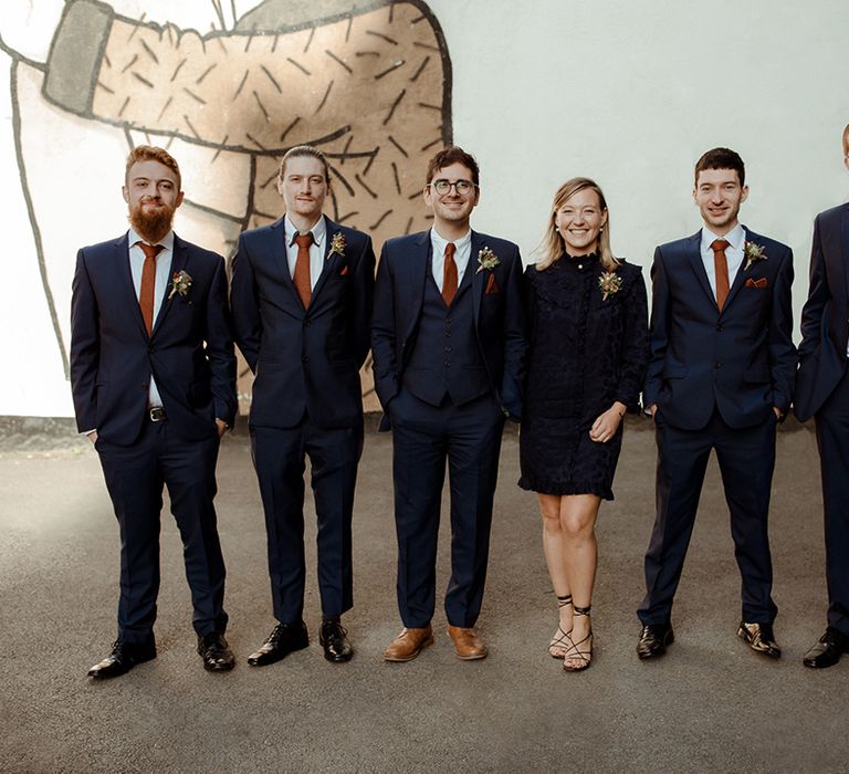 Groom's party with the men in matching navy blue suits and rust coloured ties and handkerchiefs with lady in matching blue high neck dress