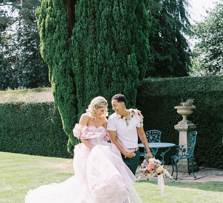 Bride in a pink flower wedding dress and groom in a white t-shirt and flower collar 