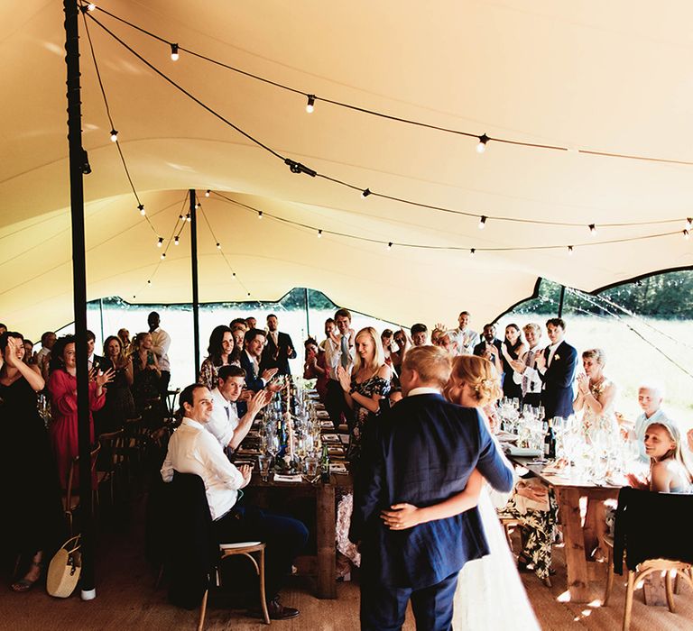 Bride and groom enter their wedding reception to applause from their wedding guests