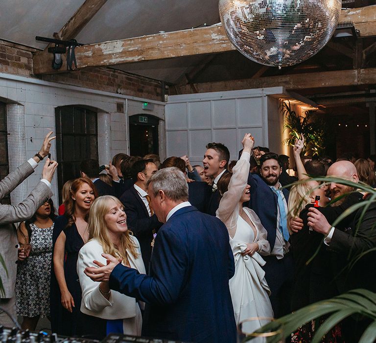 Wedding guests dance at the wedding reception with huge disco ball decor 