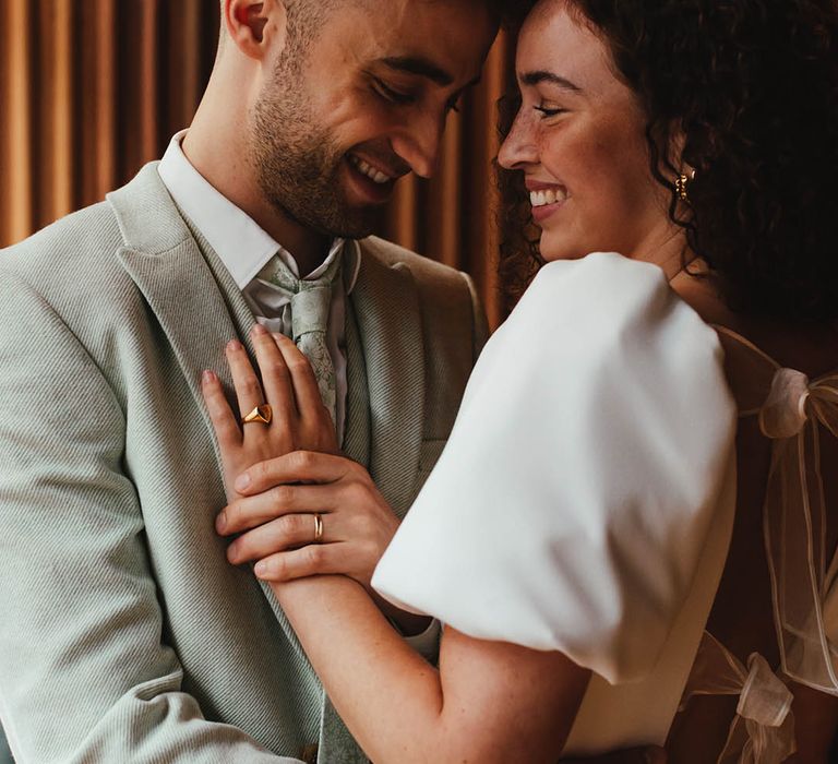 Bride in a short wedding dress with bow back detail wearing a gold signet ring 