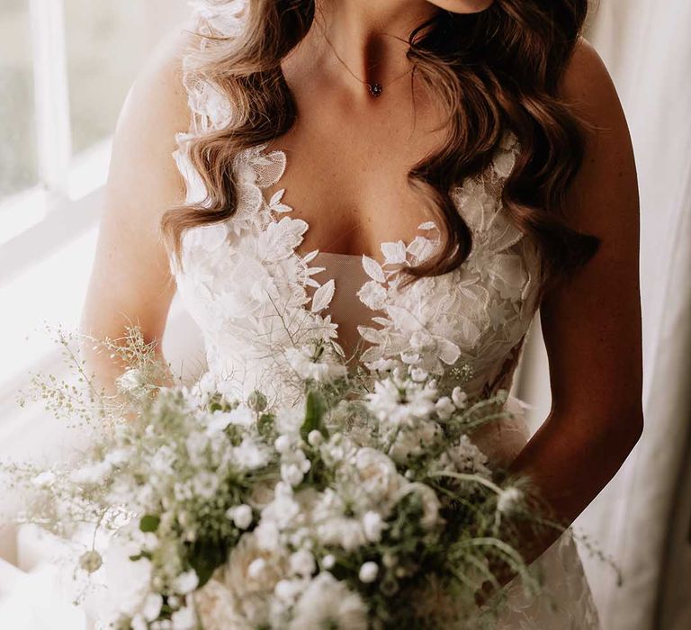 Bride with white wedding bouquet in floral wedding dress with diamanté gold earrings 