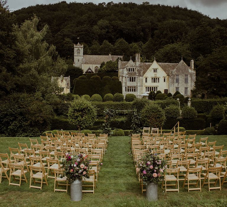 Outdoor wedding ceremony setup at Owlpen Manor with wooden chairs and pink wedding flowers 