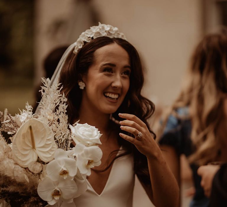 Bride holding an orchid bridal bouquet with white flower earrings and bridal headband in v-neck wedding dress