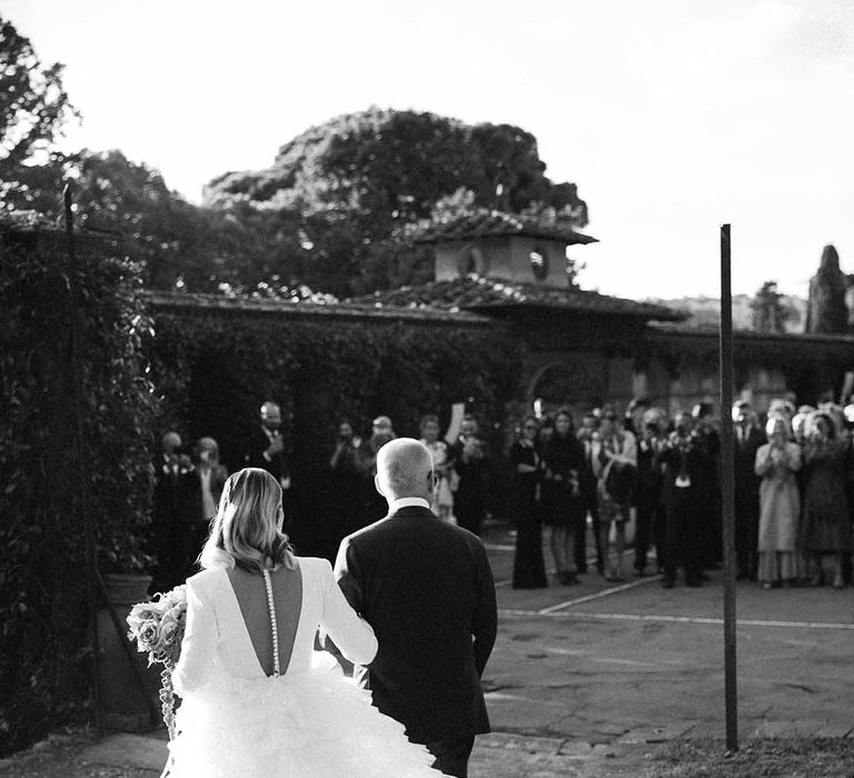 Bride wears Milla Nova wedding gown with extravagant tulle train, long sleeves and buttoned back 