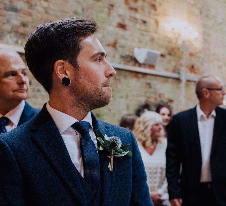 Groom in a blue suit and wearing a thistle buttonhole gets his first look at the bride 