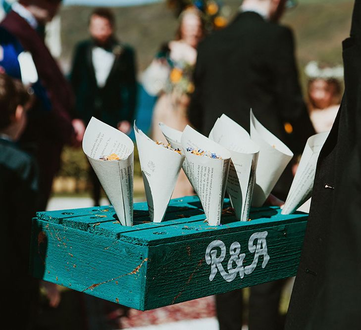 Colourful confetti in white paper cones stood in blue wooden box painted with R&A