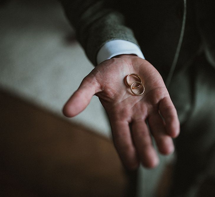 Groom holds gold wedding bands on the morning of his wedding day