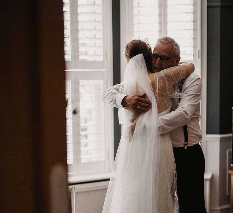 Bride hugs her father as he sees her in her wedding dress for the first time 