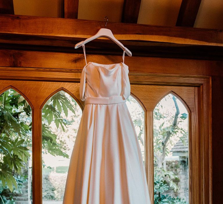 The bride's wedding dress from Love and Loved Bridal hangs up 