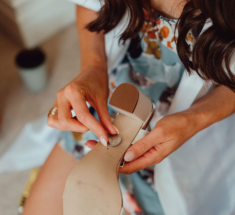 Wedding guest attaches a penny to the bride's wedding shoe for some good luck 