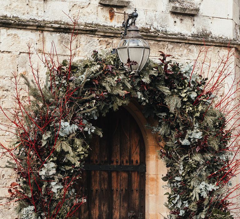 Winter festive wedding flower arch with red twigs, leaves, and foliage 