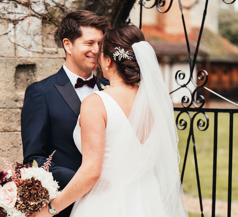 Bride with sparkly hair accessory facing the groom in black tie for their Notley Abbey wedding 