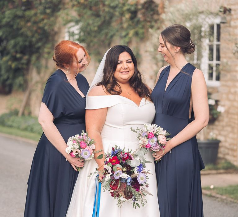 Midnight blue satin bridesmaid dresses with the bride in an off the shoulder Essense of Australia dress for Stratton Court Barn Bicester wedding 