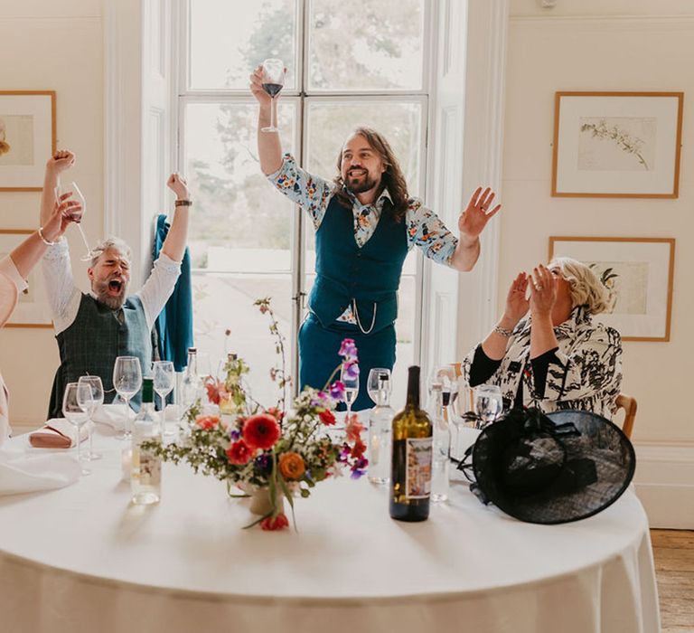 Grooms laugh during wedding speeches for wedding in Kew Gardens