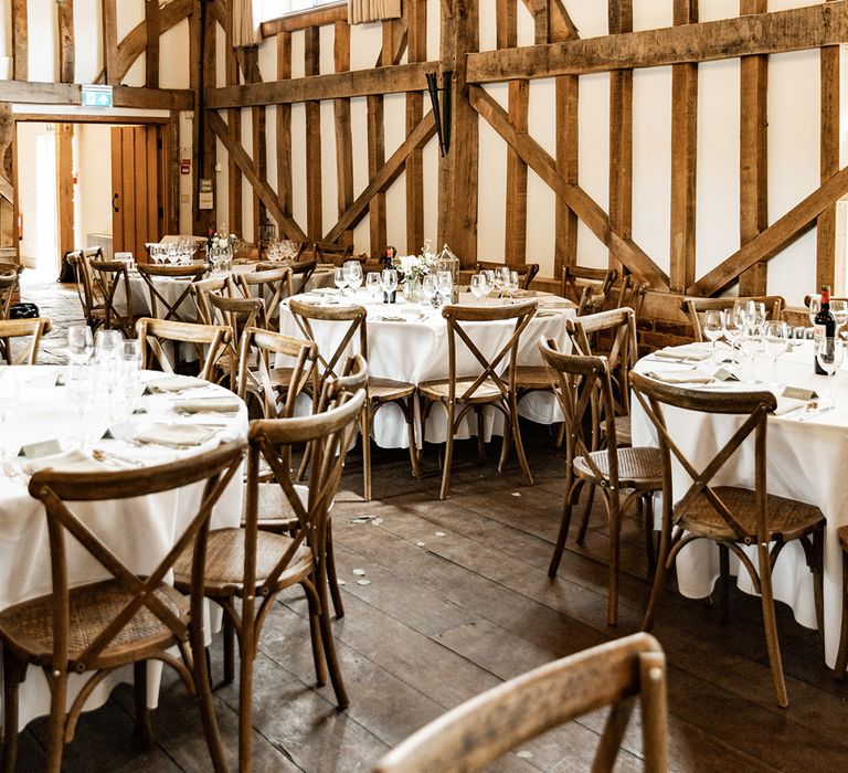 Rustic barn wedding venue complete with wooden beams and round tables covered in white table cloth