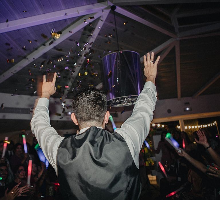 wedding guest raising hands at evening reception with foil confetti cannon