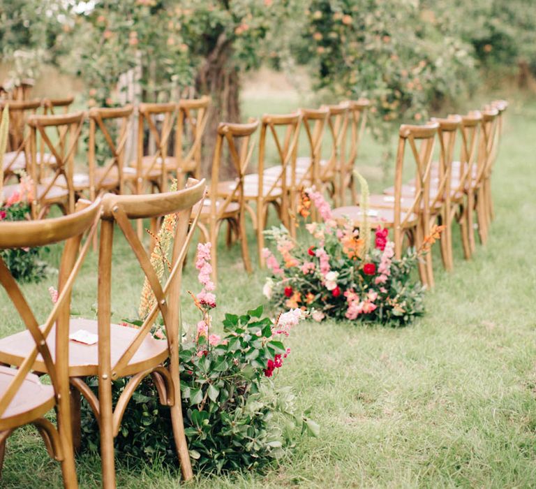 Wildflower botanical wedding aisle decor with dark pink, light pink, and orange flowers for outdoor wedding ceremony 