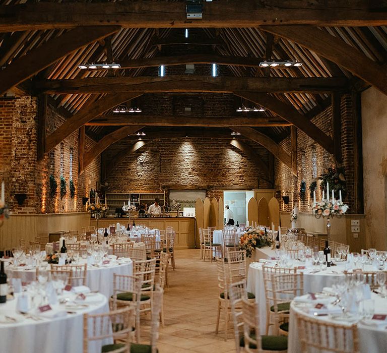 Elms Barn wedding venue in Suffolk with warm toned orange and peach flowers on tall gold candelabras for the table centrepieces 