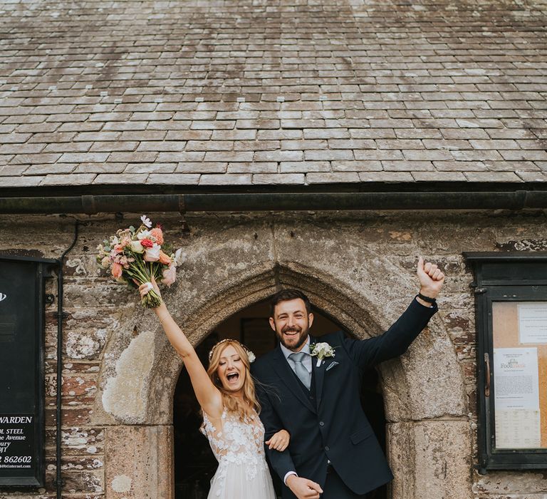 Bride in tulle Anna Kara wedding dress celebrating with the groom in wedding suit after their church wedding ceremony 