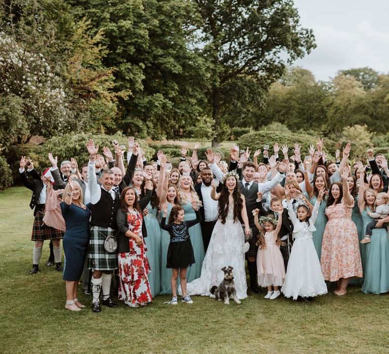 Wide shot of wedding party alongside bride and groom at outdoor wedding venue 