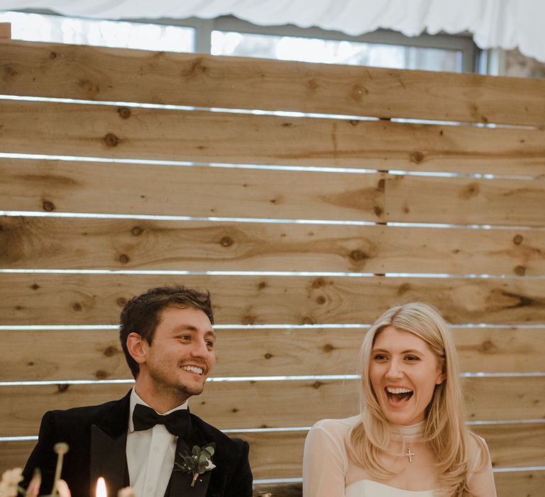 The bride and groom laugh together during the wedding speeches 