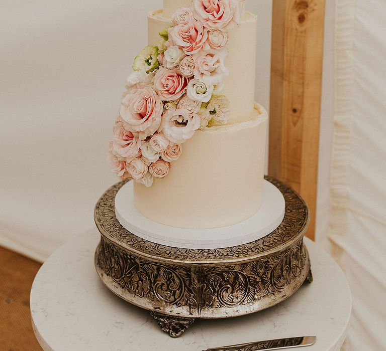 Three tier white frosted wedding cake with pink roses in stunning arrangement