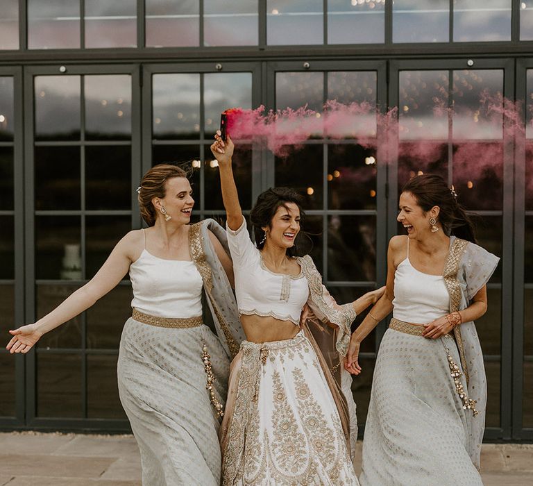 Bride walking with bridesmaids to pink smoke flare for fun wedding bridal party photo