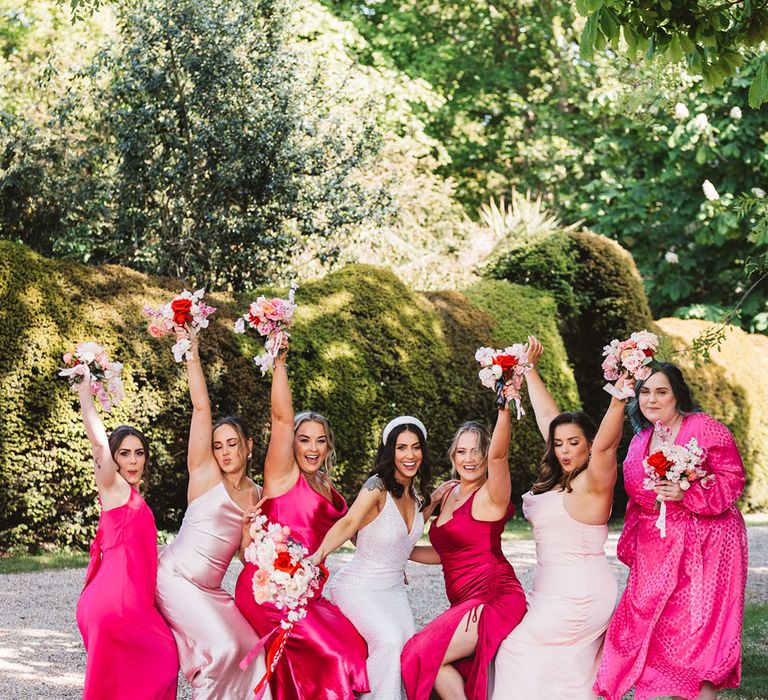 Light baby pink and bright pink mismatched bridesmaid dresses with bride wearing chunky headband 