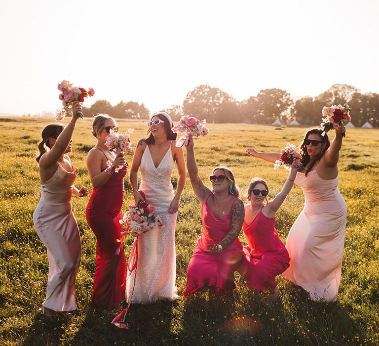 Bridesmaids in satin pink mismatched dresses with the bride in a sparkly wedding dress 