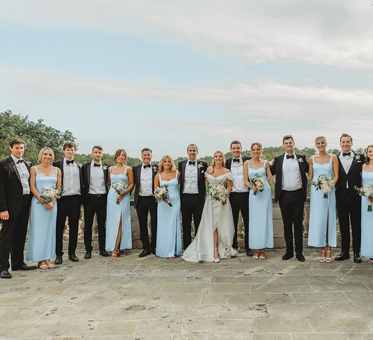 Group wedding party photo with black tie dress code with black tuxedos and powder blue bridesmaid dresses 