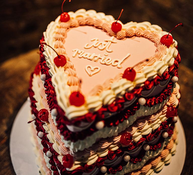 Heart shaped wedding cake for Valentine's theme wedding with pink and red colour palette with cherries decorating the cake 