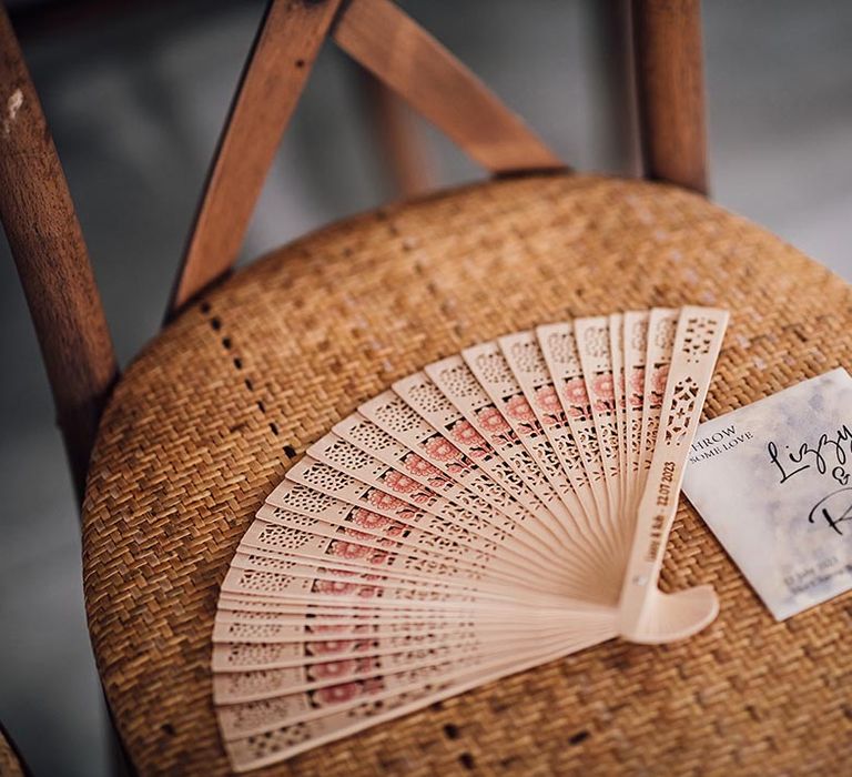 Wooden wedding fan on rattan chairs and personalised pouch of confetti 