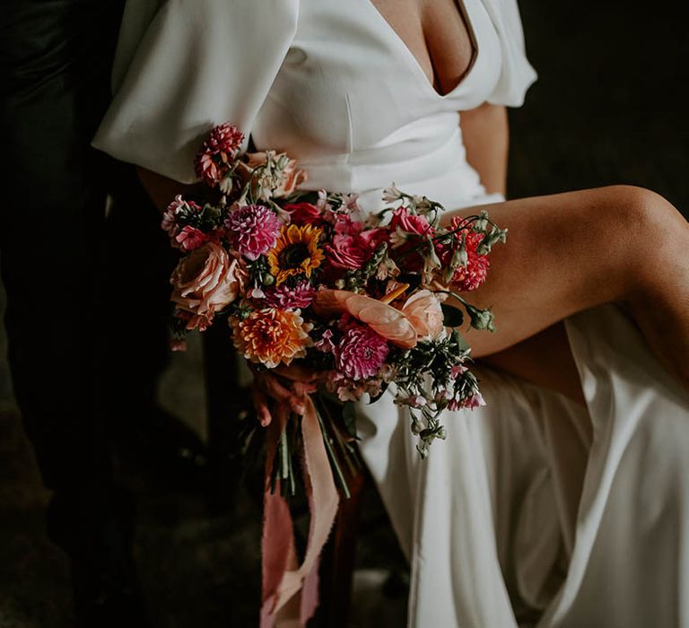 Bride holding pink and orange wedding bouquet with dahlias, sunflowers and roses 